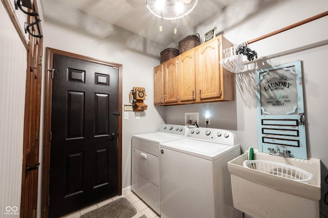 washroom featuring cabinet space, light tile patterned floors, washer and dryer, and a sink