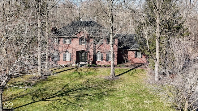 colonial inspired home featuring brick siding and a front lawn