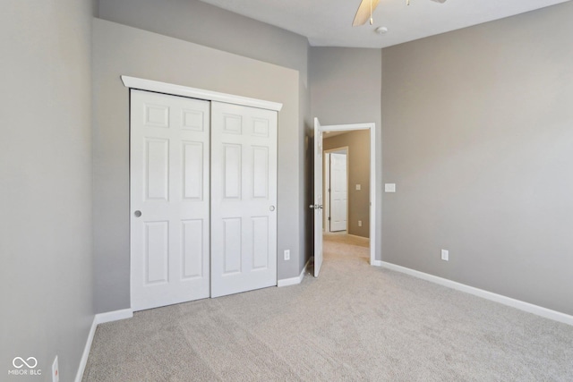 unfurnished bedroom featuring a closet, baseboards, light colored carpet, and ceiling fan