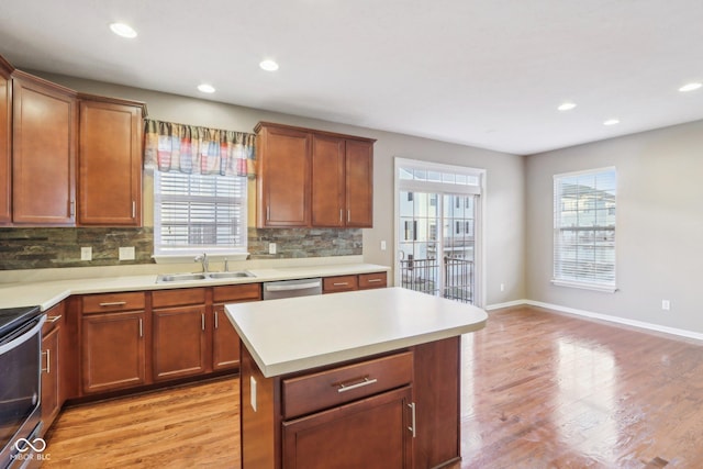 kitchen featuring light wood finished floors, plenty of natural light, appliances with stainless steel finishes, and a sink