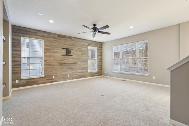 empty room featuring recessed lighting, baseboards, carpet, and wooden walls