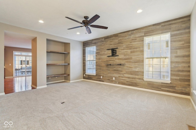 carpeted spare room with wooden walls, recessed lighting, baseboards, and built in features