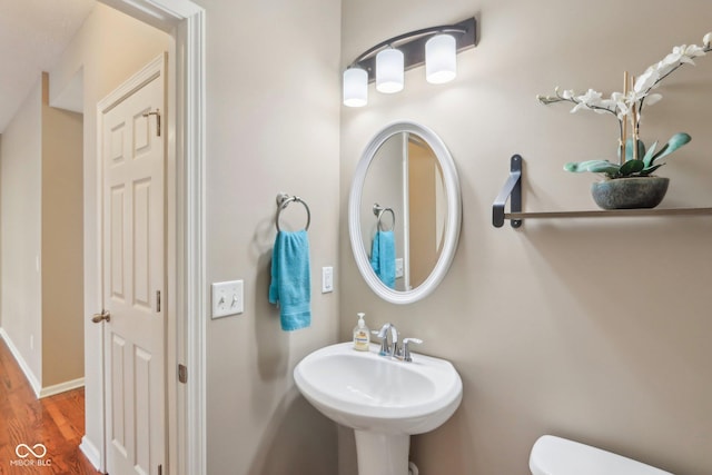 bathroom featuring a sink, baseboards, toilet, and wood finished floors