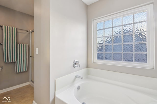 full bathroom featuring baseboards, a bath, a shower stall, and tile patterned flooring