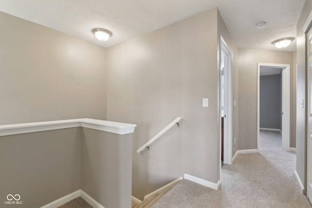 hall with baseboards, an upstairs landing, and carpet