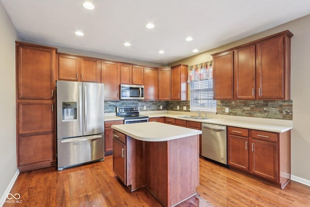 kitchen with stainless steel appliances, tasteful backsplash, light wood-style floors, and light countertops