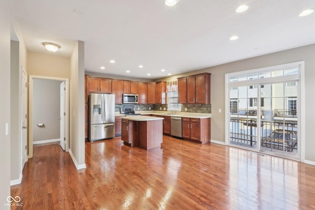 kitchen featuring a center island, light countertops, decorative backsplash, light wood-style flooring, and stainless steel appliances