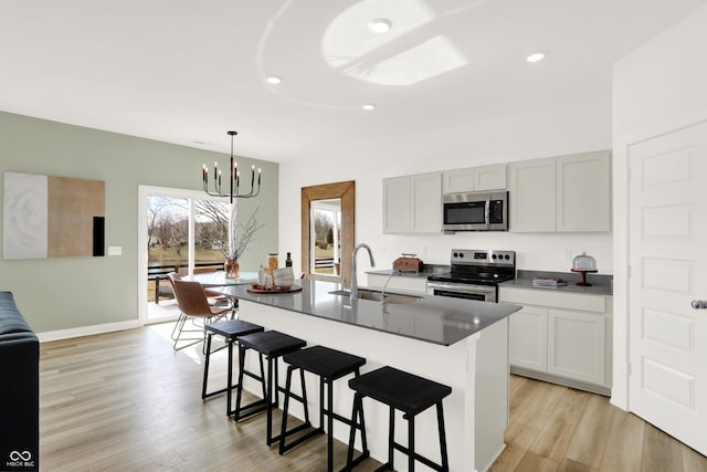 kitchen featuring a breakfast bar, an inviting chandelier, a sink, stainless steel appliances, and light wood-type flooring