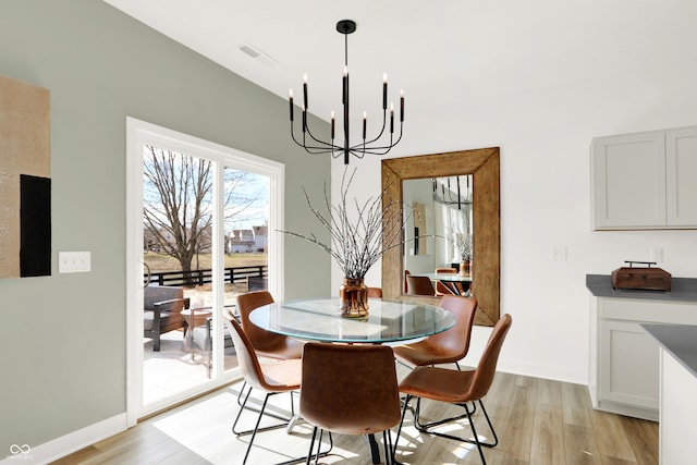 dining area with a notable chandelier, light wood-style flooring, visible vents, and baseboards