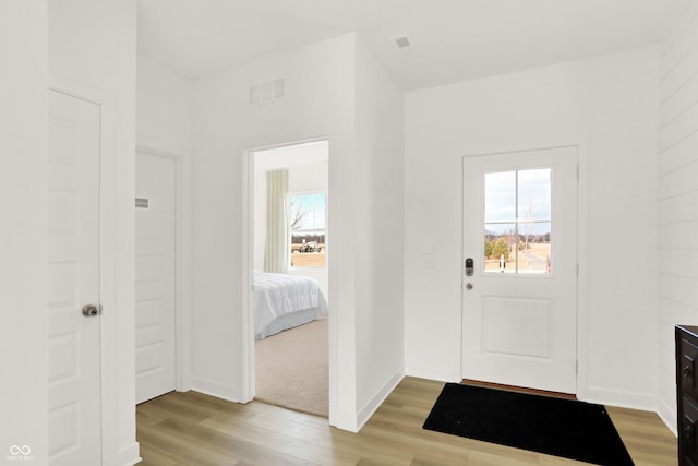 foyer entrance with visible vents, a wealth of natural light, and light wood-type flooring