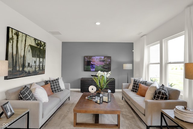 living room with light carpet, visible vents, and baseboards