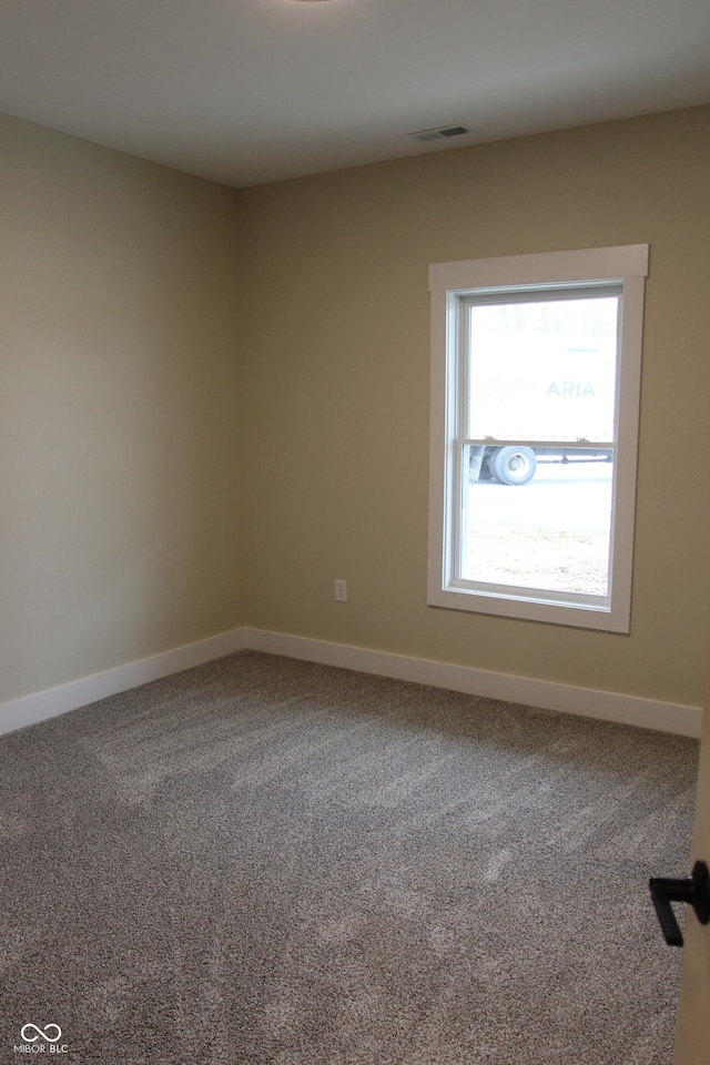 spare room with visible vents, baseboards, and carpet