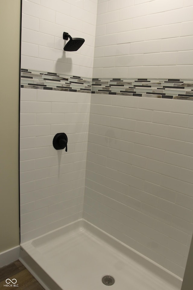 full bathroom featuring baseboards, wood finished floors, and a stall shower