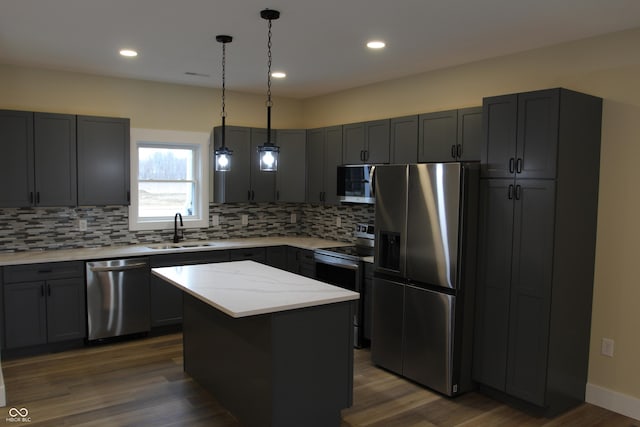 kitchen featuring dark wood finished floors, decorative backsplash, appliances with stainless steel finishes, and a sink