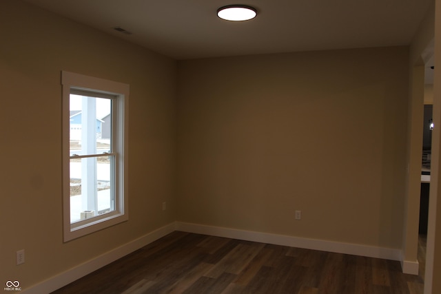 spare room featuring dark wood finished floors and baseboards