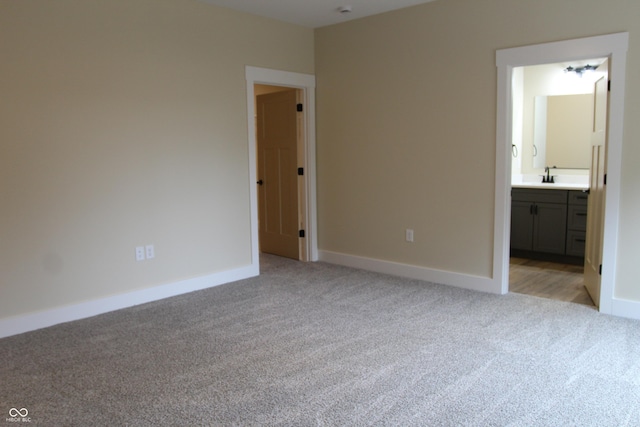 unfurnished bedroom with a sink, baseboards, and light colored carpet