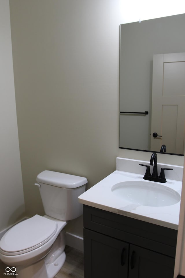 bathroom with toilet, wood finished floors, and vanity