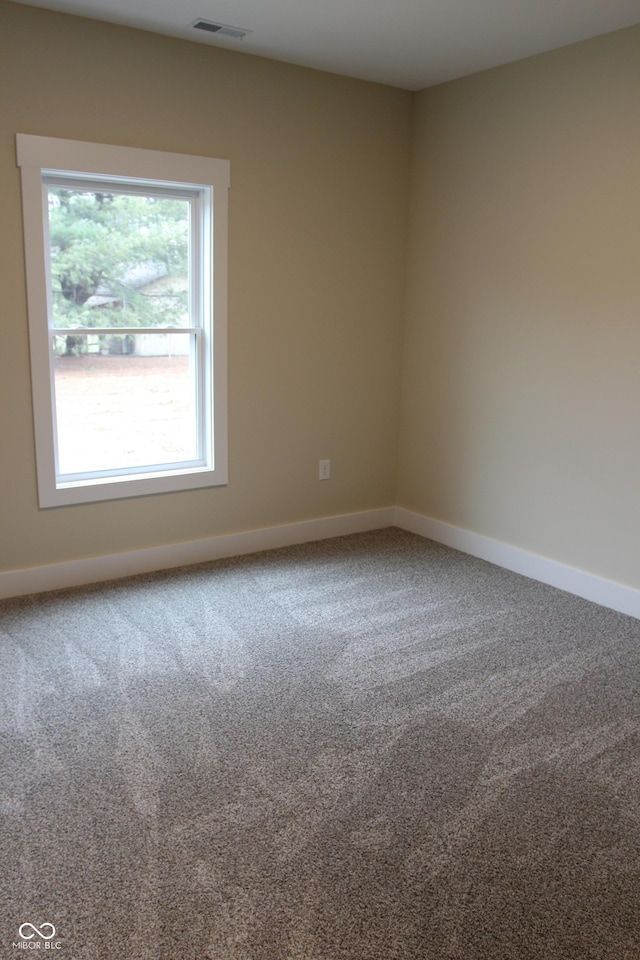 empty room featuring carpet, visible vents, and baseboards