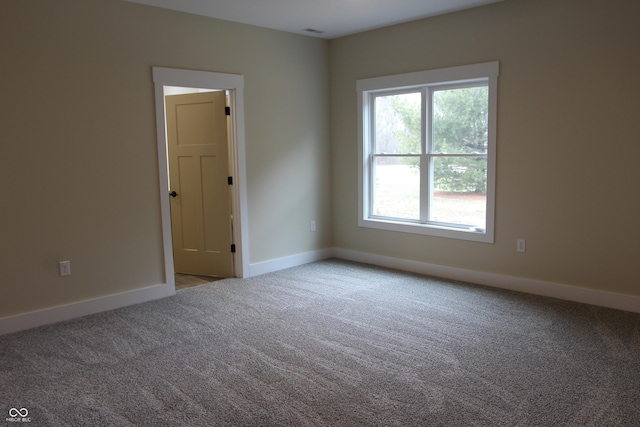 carpeted spare room with visible vents and baseboards