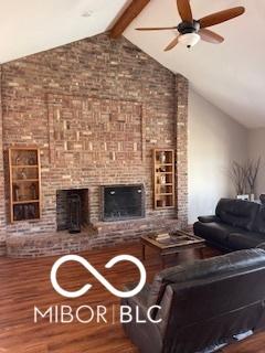 unfurnished living room featuring a brick fireplace, vaulted ceiling with beams, and wood finished floors