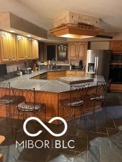 kitchen featuring a breakfast bar, light countertops, a peninsula, stainless steel appliances, and a sink