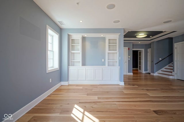 spare room featuring stairway, visible vents, baseboards, and light wood-style floors