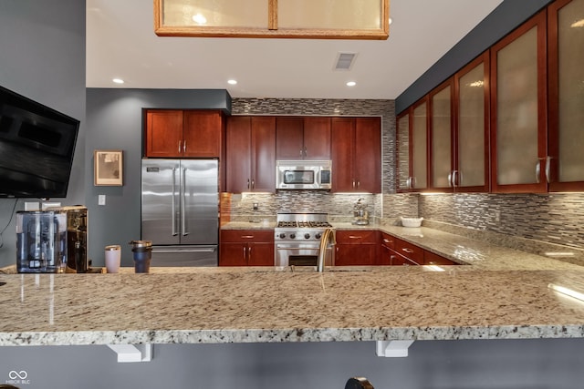 kitchen featuring premium appliances, backsplash, visible vents, and light stone countertops