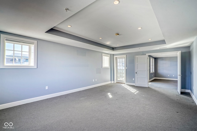 unfurnished room with baseboards, a raised ceiling, carpet, and plenty of natural light