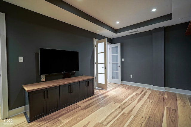 unfurnished living room with visible vents, a raised ceiling, baseboards, and light wood finished floors