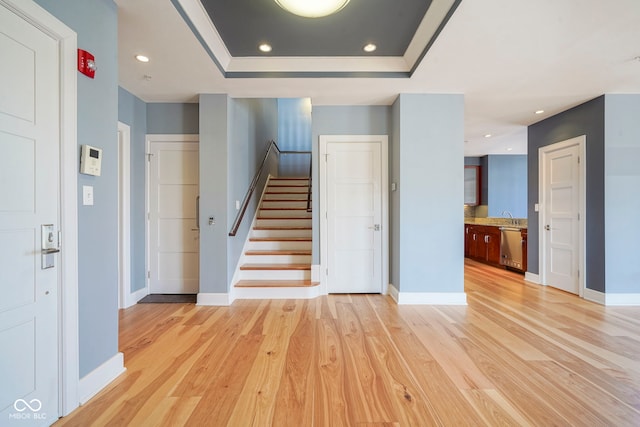 stairway with a tray ceiling, recessed lighting, wood finished floors, and baseboards