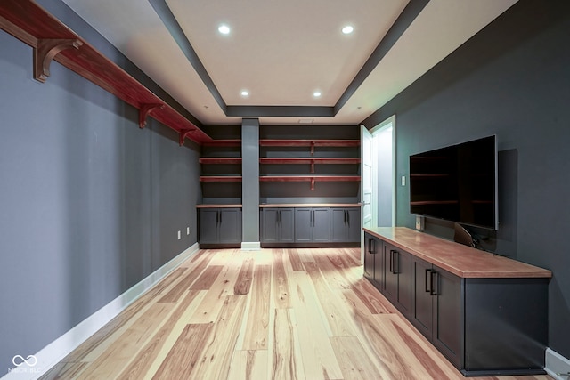 interior space featuring a tray ceiling, light wood-style flooring, recessed lighting, and baseboards