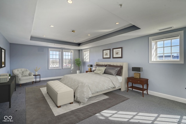 bedroom with a raised ceiling, baseboards, and visible vents