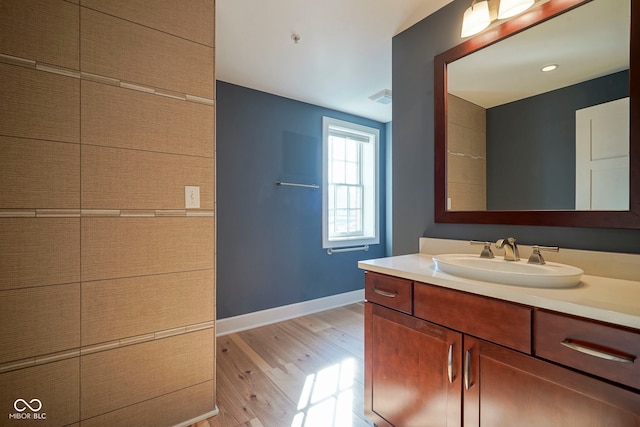 bathroom with vanity, wood finished floors, baseboards, and visible vents