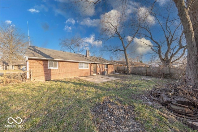 rear view of house featuring a patio, a yard, fence, and brick siding