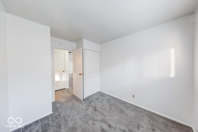 unfurnished bedroom with a closet, carpet flooring, and baseboards