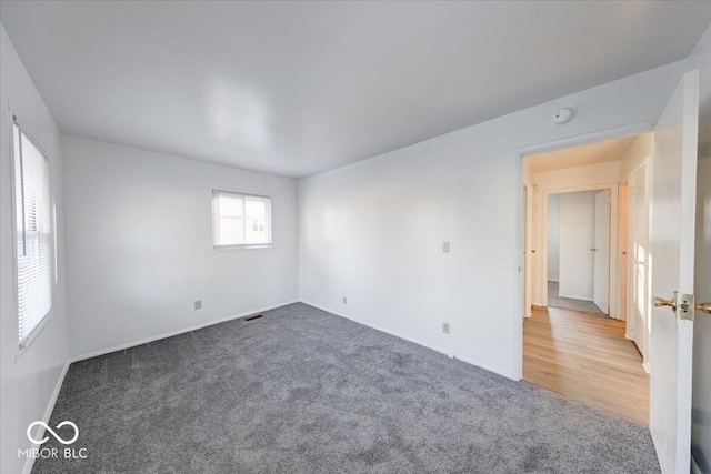 empty room featuring baseboards, visible vents, and carpet floors