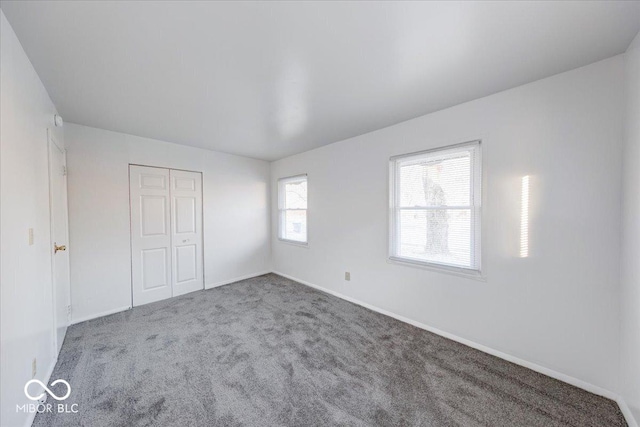 unfurnished bedroom with carpet flooring, baseboards, and a closet