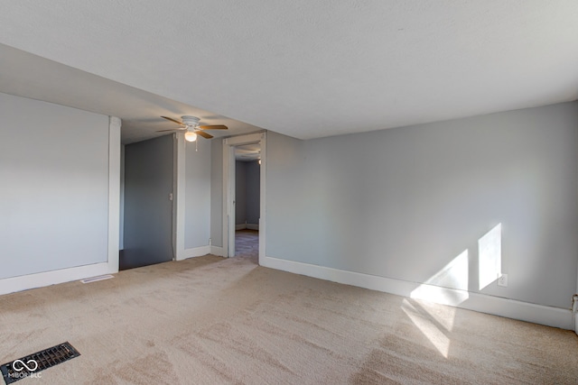 carpeted spare room featuring visible vents, baseboards, and a ceiling fan