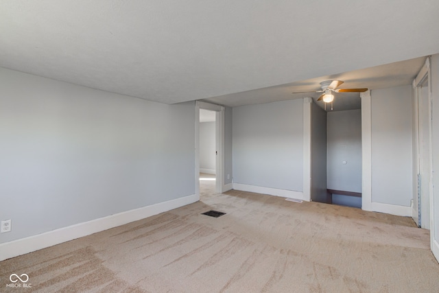 spare room with ceiling fan, light colored carpet, visible vents, and baseboards