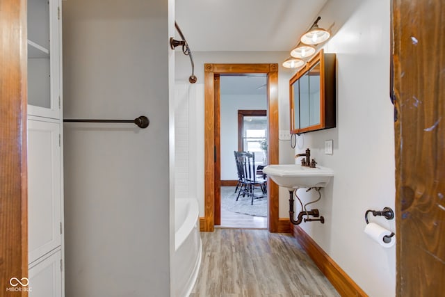 full bath featuring a sink, baseboards, and wood finished floors