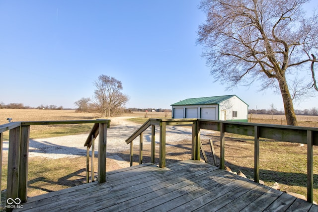 wooden terrace featuring an outdoor structure, a rural view, and a garage