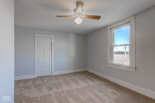 spare room featuring ceiling fan, baseboards, and light carpet