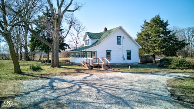 rear view of house featuring a sunroom and a chimney