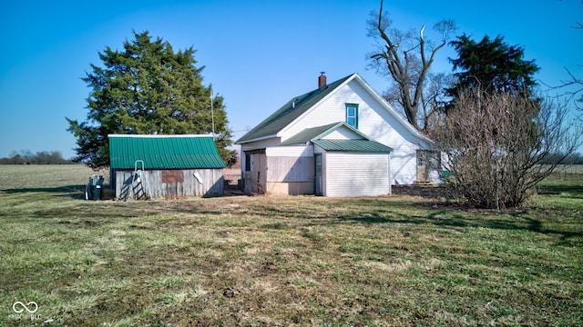 exterior space featuring an outbuilding, a lawn, and a chimney