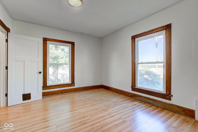 unfurnished room featuring visible vents, light wood-style flooring, and baseboards