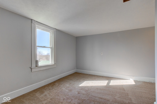 carpeted spare room featuring baseboards