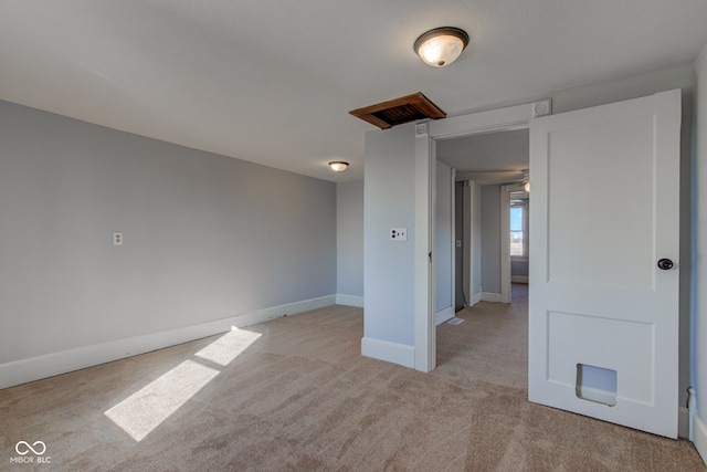 empty room featuring baseboards and light colored carpet