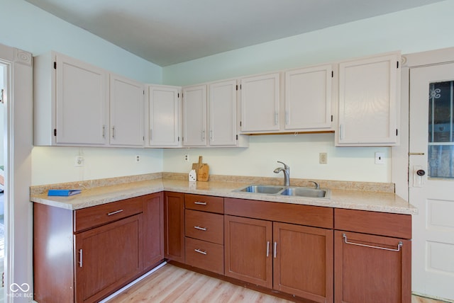 kitchen with a sink, light wood finished floors, brown cabinets, and light countertops