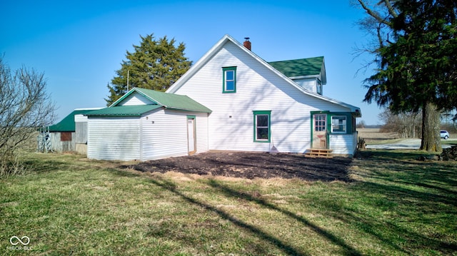 rear view of property with a lawn, entry steps, and a chimney