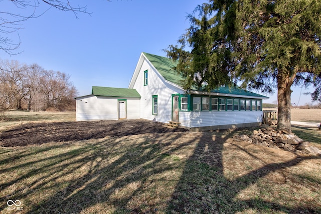 exterior space featuring entry steps, a lawn, and a sunroom